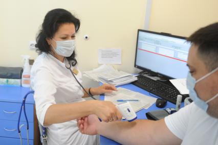 Санкт-Петербург. Врач измеряет температуру активисту Приморского района перед вакцинацией от коронавирусной инфекции в поликлинике