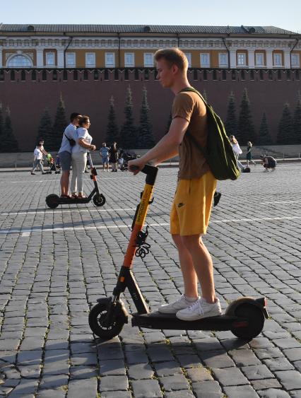 Москва. Молодой человек едет на электросамокате по Красной площади.