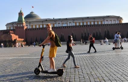 Москва. Молодой человек едет на электросамокате по Красной площади.