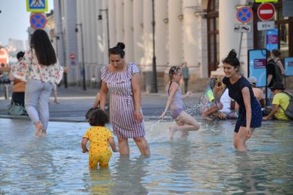 Москва. Горожане в фонтане во время жары.