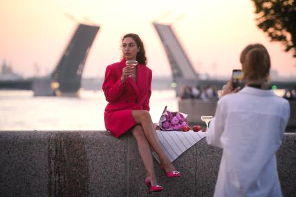 Санкт-Петербург. Девушка фотографируется с бокалом белого вина на набережной реки Невы.