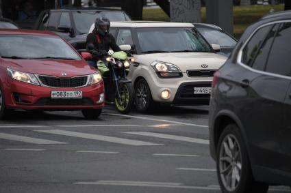 Москва. Мотоциклист стоит между машинами на дороге в ожидании `зеленого света`.