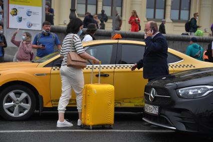 Москва. Женщина с чемоданом у такси.