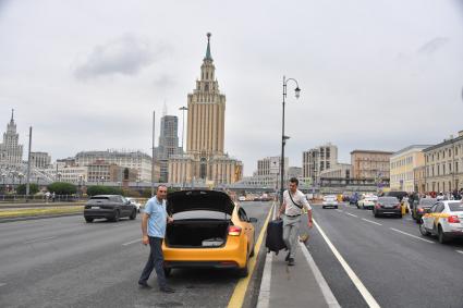 Москва. Мужчина с багажом садится в такси на Комсомольской площади.