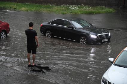 Москва. Мужчина смотрит на машину, проезжающую в потоке воды.