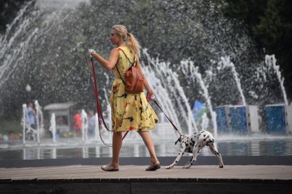 Москва. Девушка с собакой породы далматинец во время прогулки на ВДНХ.