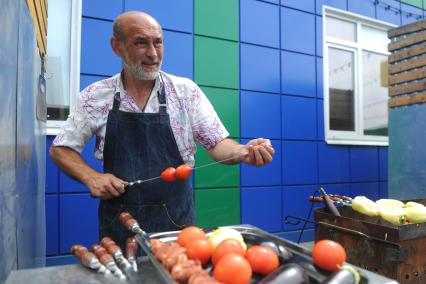 Санкт-Петербург. Шашлычник нанизывает помидоры на шампур на Южном рынке.