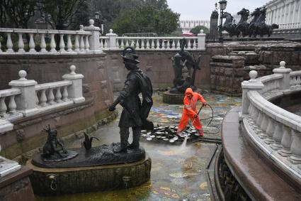 Москва.  Сотрудник коммунальных служб моет фонтан `Иван царевич и царевна лягушка`на манежной площади.