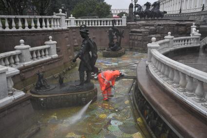 Москва.  Сотрудник коммунальных служб моет фонтан `Иван царевич и царевна лягушка`на манежной площади.