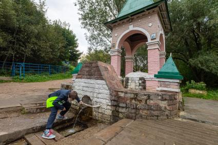 Москва.  Мальчик пьет воду из источника на экологической тропе   `У истоков рек`на территории ландшафтного заказника  Теплый Стан.