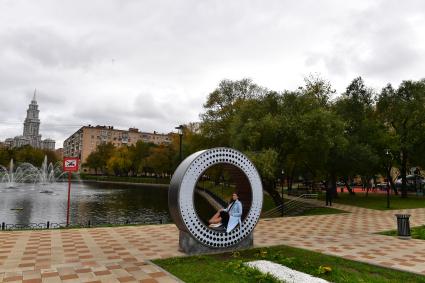 Москва. Девушка сидит на круглой скамейке в сквере у Амбулаторного пруда.