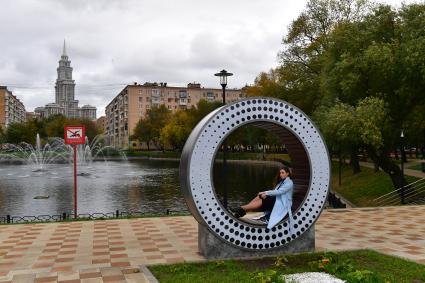 Москва. Девушка сидит на круглой скамейке в сквере у Амбулаторного пруда.