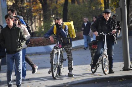 Москва.  Сотрудник службы доставки на пешеходном переходе.