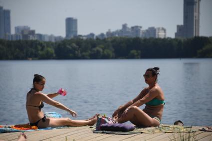 Москва. Пляж в Строгино. Девушки загорают на настиле.