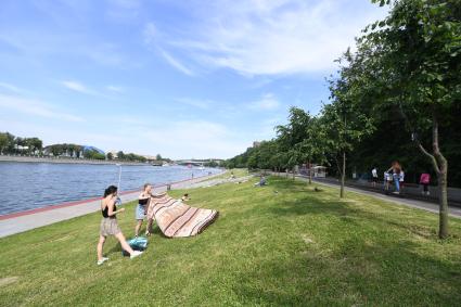 Москва. Пляж на территории Воробьевых гор. Девушки стелят покрывало на траве.