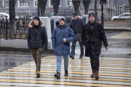 Пермь. Первый снег в городе. Молодые люди переходят дорогу по пешеходному переходу.