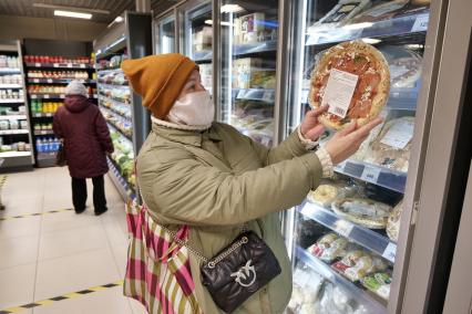 Самара. Женщина держит в руках замороженную пиццу в продуктовом магазине.
