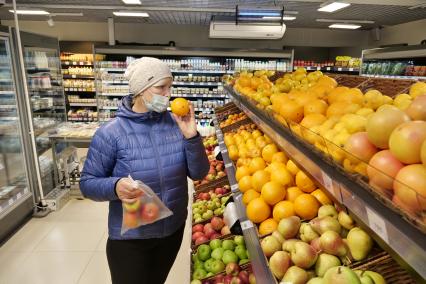 Самара. Женщина выбирает апельсины в продуктовом магазине.