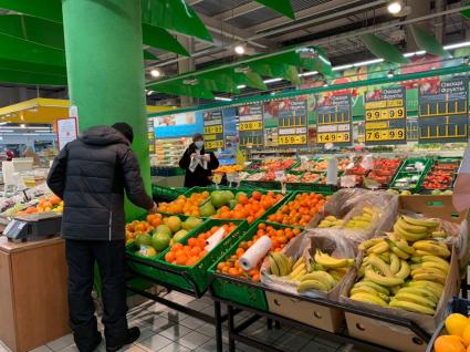 Томск. Мужчина выбирает апельсины в продуктовом магазине.