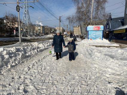 Томск. Женщина с ребенком идут по тротуару на одной из улиц города.