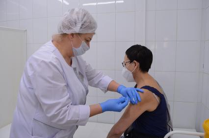 Томск. Медсестра делает женщине прививку от коронавирусной инфекции Covid-19 в прививочном пункте больницы.