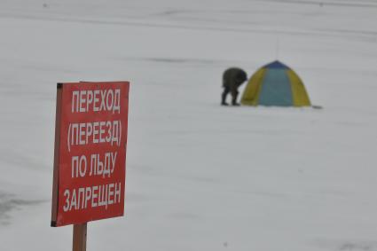 Екатеринбург. Рыбак на льду городского пруда под табличкой с надписью \'переход (переезд) по льду запрещен\'