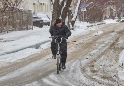 Пермь. Мужчина  на велосипеде  на заснеженной улице.