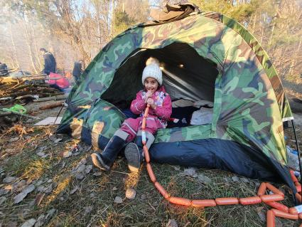 Белорусско-польская граница. Ребенок беженцев из Ближнего Востока ест сосиски в лагере нелегальных мигрантов.