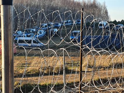 Белорусско-польская граница. Польские полицейские автомобили стоят по другую сторону от лагеря нелегальных мигрантов, где находятся беженцы из Ближнего Востока.