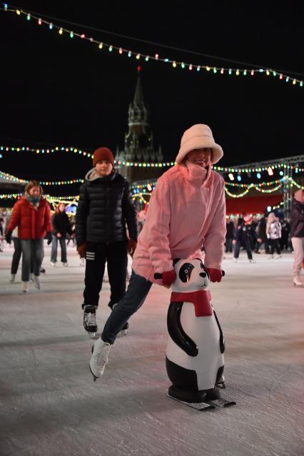 Москва. Девушка катается на коньках с помощью поддерживающей стойки на открытии ГУМ-катка на Красной площади.