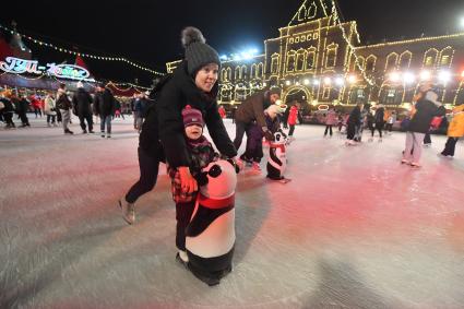 Москва. Женщина с ребенком катаются на коньках с помощью поддерживающей стойки на открытии ГУМ-катка на Красной площади.