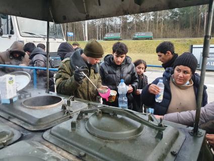 Белорусско-польская граница. Военнослужащий разливает кипяток для беженцев из Ближнего Востока в центре временного содержания мигрантов.