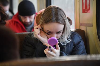Москва. Девушка красит ресницы в пригородной электричкею