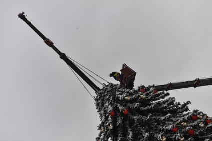 Москва.   Рабочие устанавливают новогоднюю елку на Манежной площади во время снегопада.