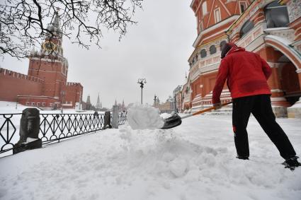 Москва.   Сотрудник коммунальных служб убирает снег на Васильевском спуске.