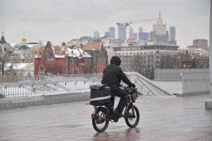 Москва. Сотрудник службы доставки на  мопеде.