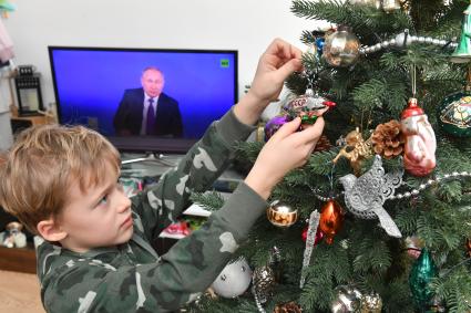 Москва. Мальчик наряжает новогоднюю елку во время просмотра трансляции ежегодной пресс-конференции президента РФ Владимира Путина.