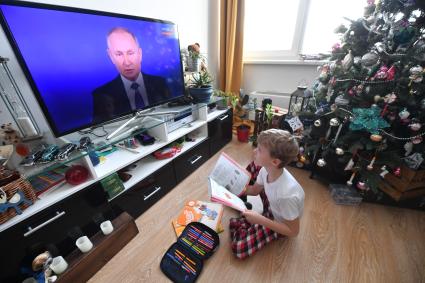 Москва. Мальчик с книгой в руках во время просмотра трансляции ежегодной пресс-конференции президента РФ Владимира Путина.