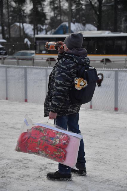 Москва.  Мужчина с покупками на улице города.