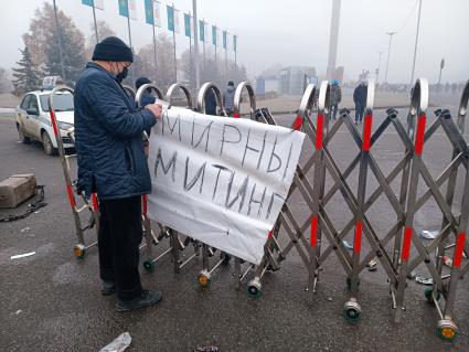 Казахстан. г.Алма-Ата. Мужчина вешает на ограждение плакат `Мирный митинг`. В Казахстане прошли массовые акции протестов, вызванные ростом цен на сжиженный нефтяной газ, которые потом переросли в беспорядки и погромы.