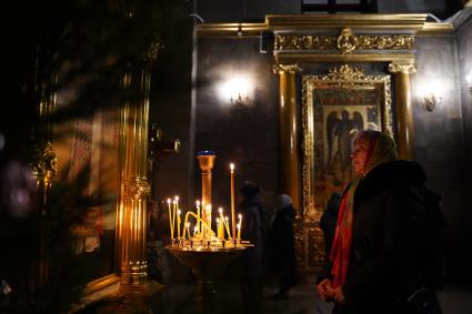 Самара.  Женщина ставит свечу во время ночной Рождественской службы.