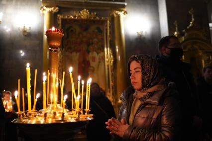 Самара.  Женщина ставит свечу во время ночной Рождественской службы.