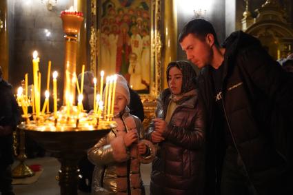 Самара.  Женщина ставит свечу во время ночной Рождественской службы.