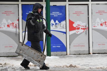 Москва. Дворник убирает снег на Ярославском вокзале. Надпись на двери `Москва приветствует вас!`.