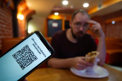 Санкт-Петербург. QR-код на экране мобильного телефона в кафе.