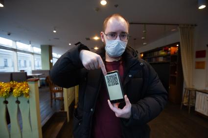 Санкт-Петербург. Мужчина демонстирует QR-код на экране мобильного телефона при входе в ресторан.