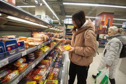 Санкт-Петербург. Девушка выбирает сосиски в продуктовом магазине.