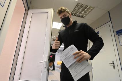 Санкт-Петербург. Юноша выходит с медицинской картой из пункта вакцинации от коронавирусной инфекции в поликлинике.