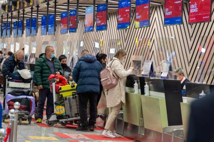 Москва. Пассажиры у стойки оформления документов в Международном аэропорту Шереметьево имени А. С. Пушкина.