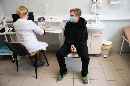 Санкт-Петербург. Врач проводит осмотр пациента перед вакцинацией от коронавирусной инфекции COVID-19 вакциной `Спутник М` в детской поликлинике #10.